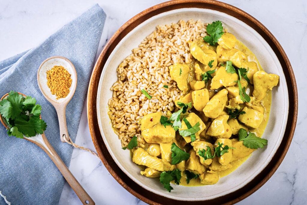 chicken curry Instant Pot being served in a bowl with rice and cilantro garnish