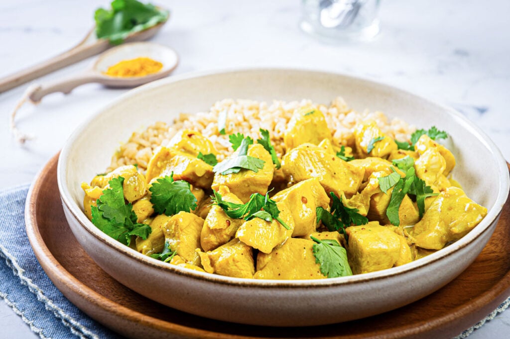 pressure cooker indian chicken curry with brown rice and cilantro in a bowl for serving