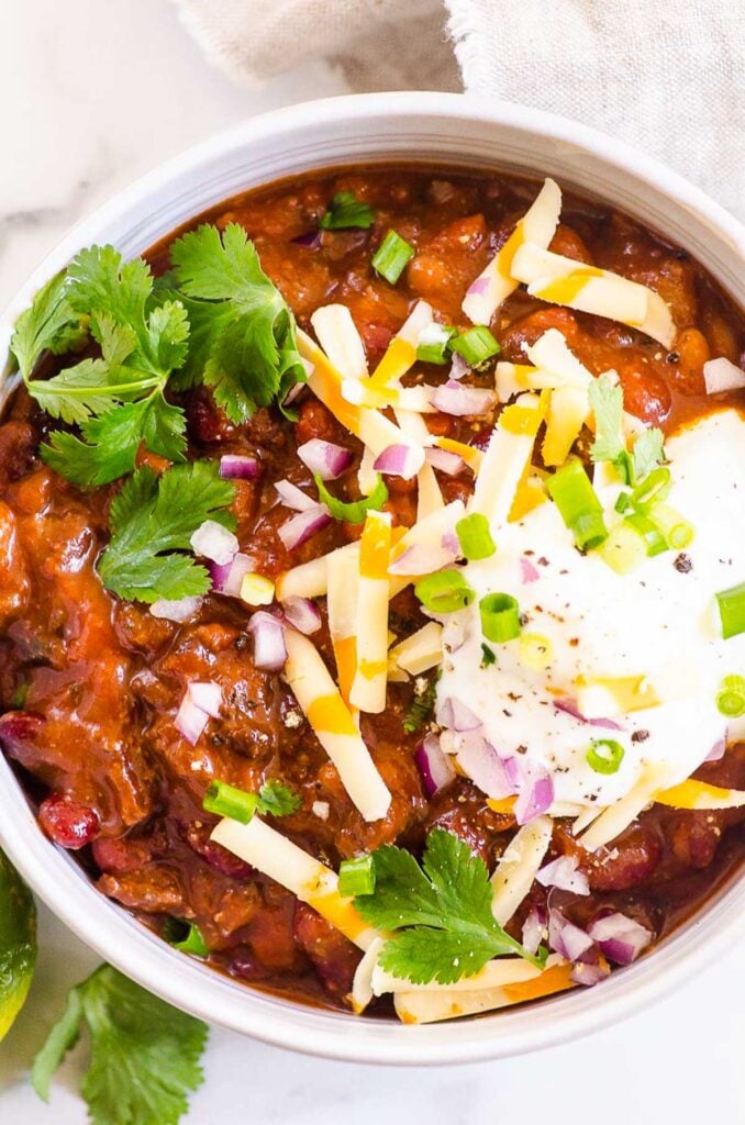 instant pot chili with beans and ground beef topped with cheese sour cream and cilantro