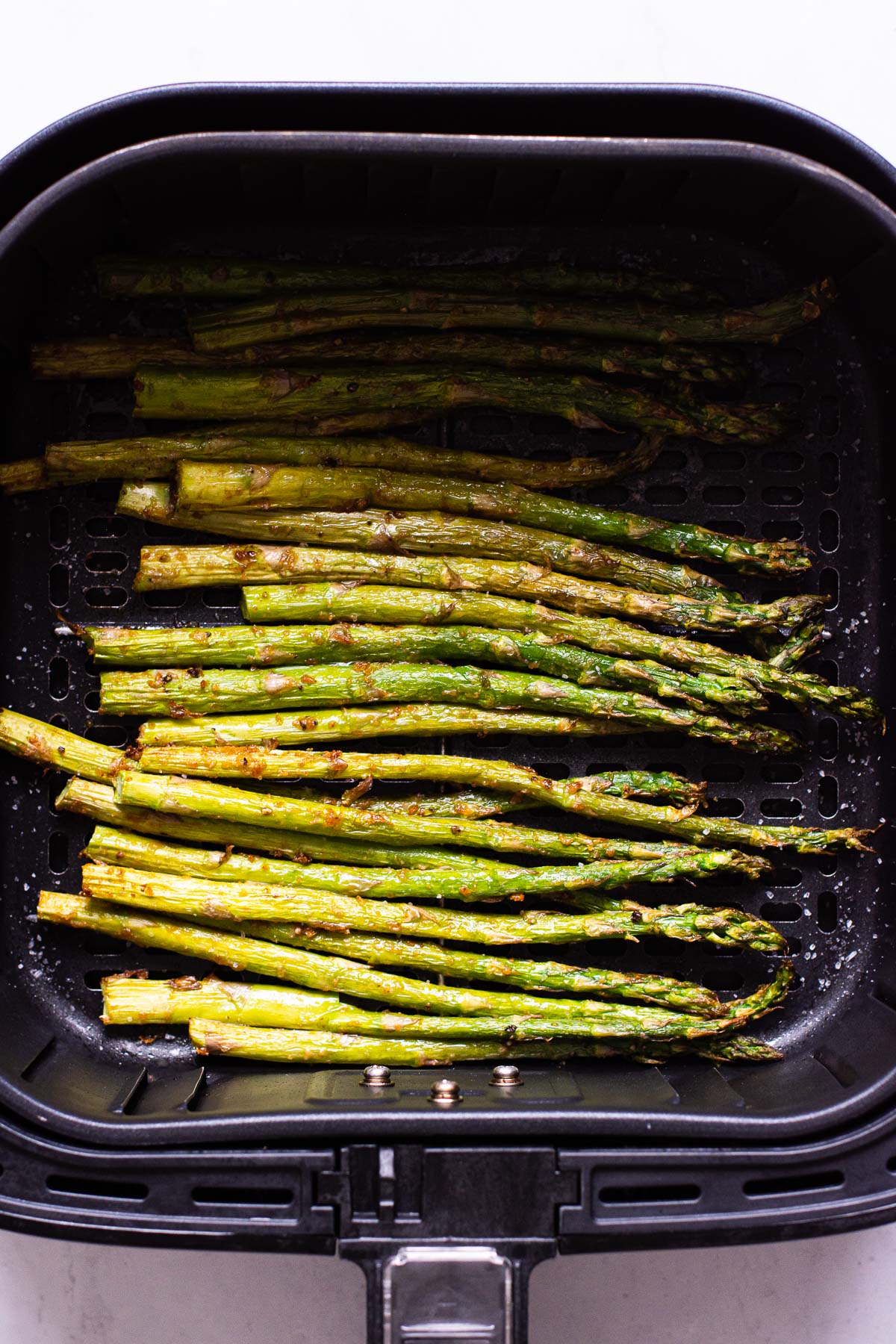 Air fryer asparagus in air fryer basket.