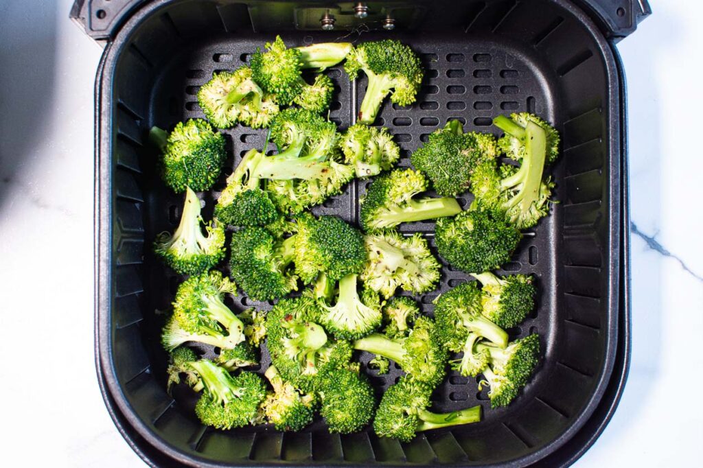 seasoned raw broccoli in an air fryer