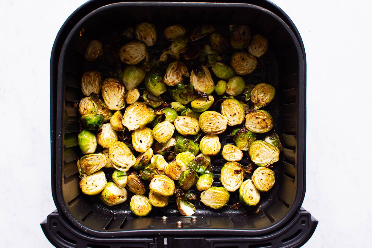 Air fried brussels sprouts in a basket of air fryer.