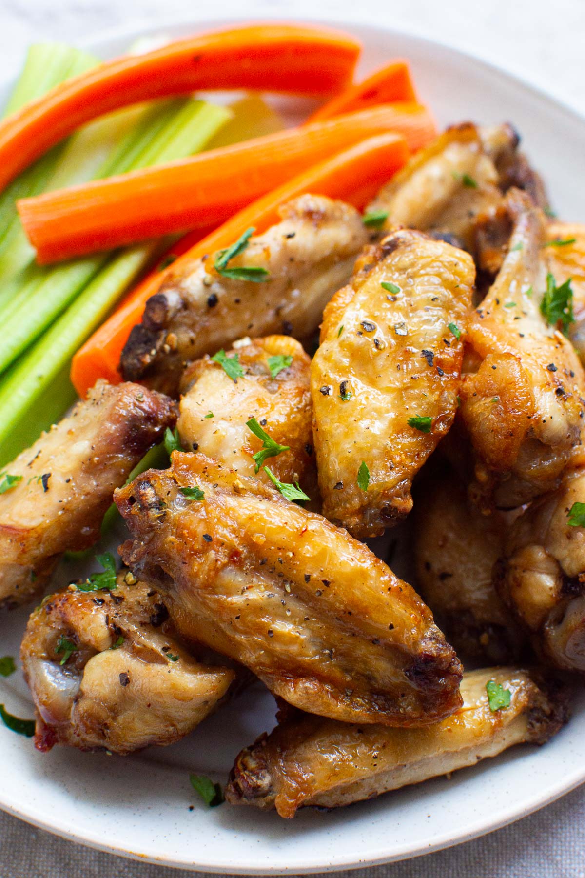 Air fryer chicken wings with carrots and celery on a plate.