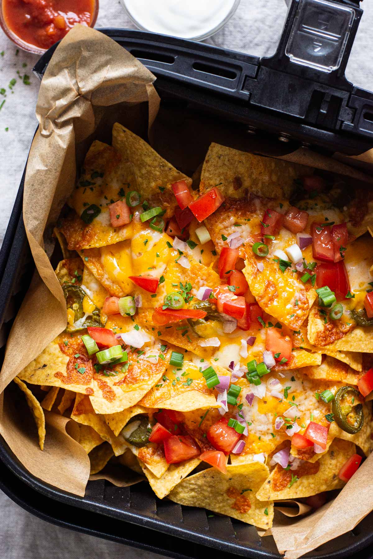 Air fryer nachos with cheese, tomatoes and green onion.