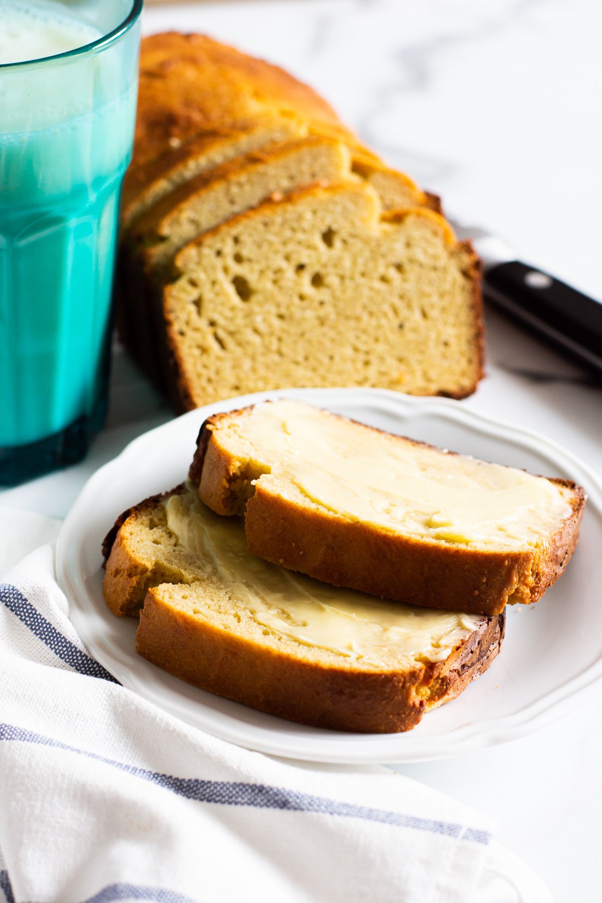 Sliced almond flour bread on plate with a glass of milk.
