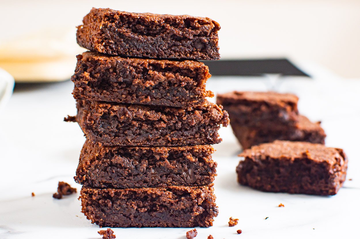 A stack of five almond flour brownies with three brownies in background.