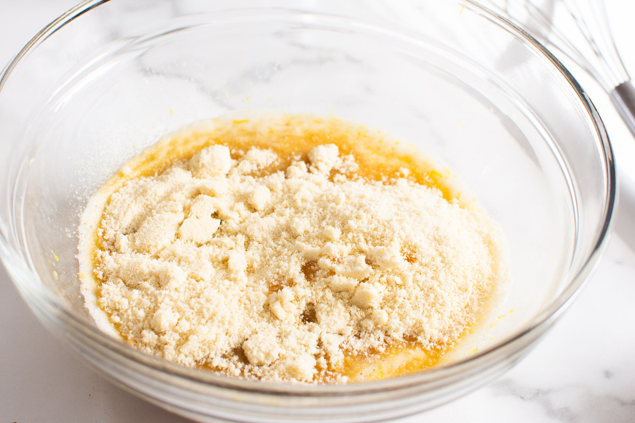 Adding almond flour to wet ingredients in bowl. 