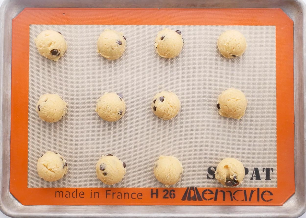 Round cookie dough balls on silpat lined baking sheet. 
