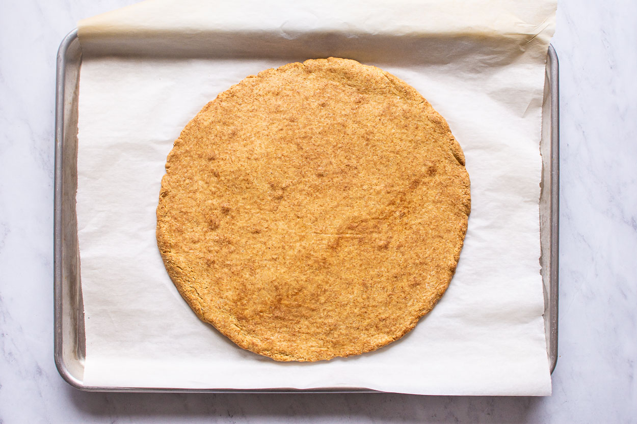 Baked almond flour pizza crust on baking sheet.