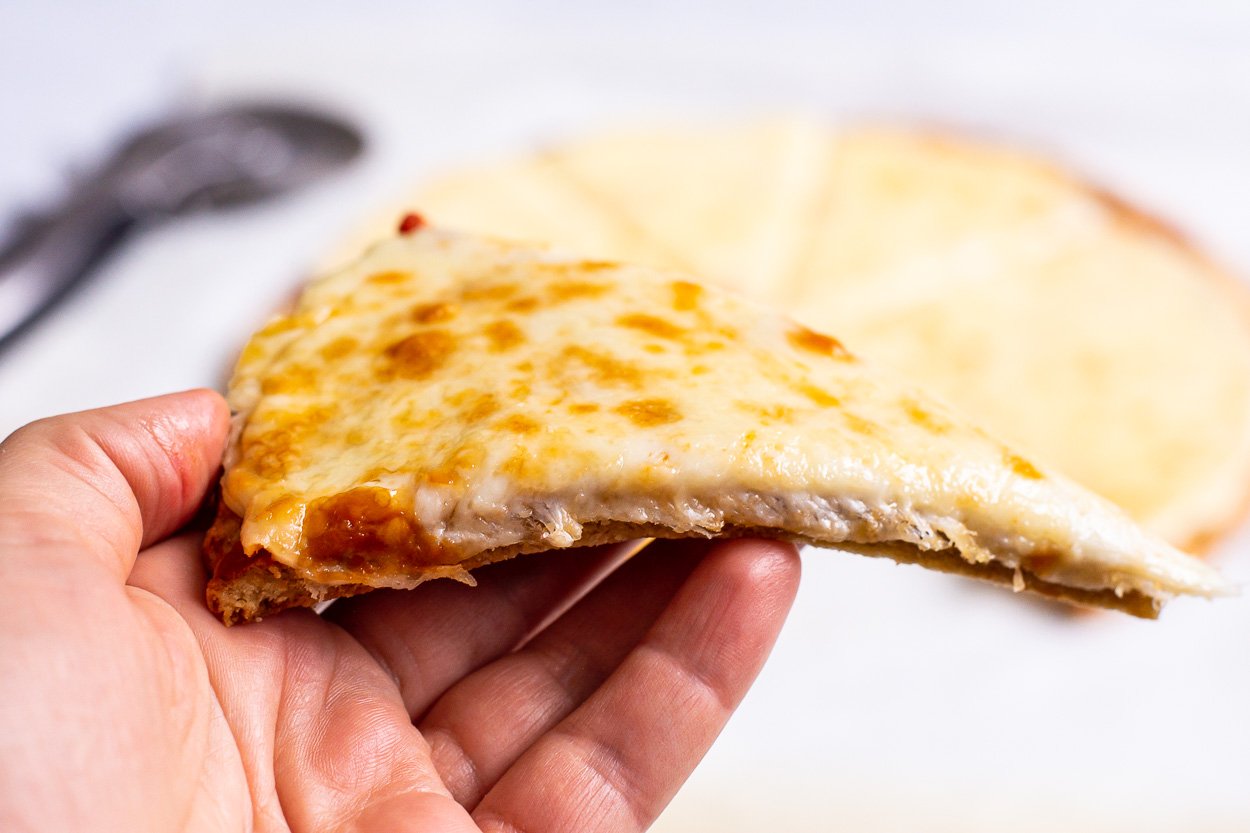 Hand holding almond flour pizza slice.