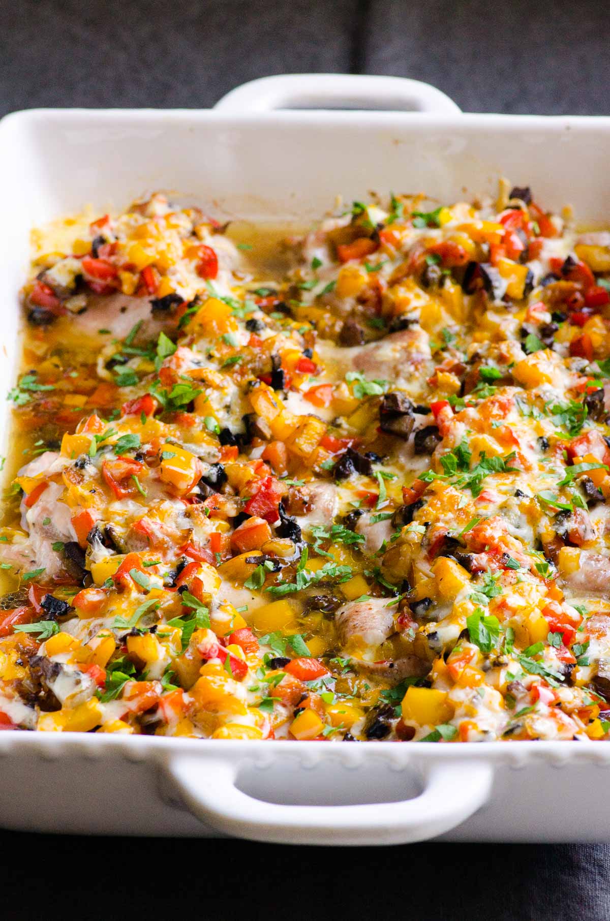 Baked chicken and peppers in white baking dish.