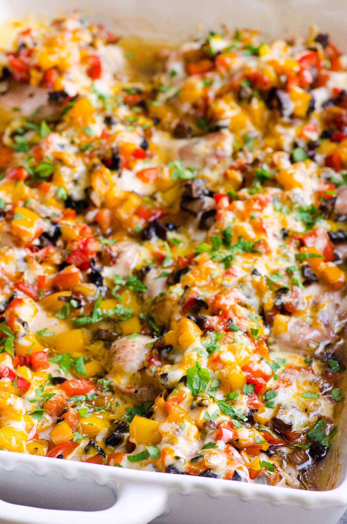 Baked chicken, mushrooms and peppers topped with cheese in baking dish.