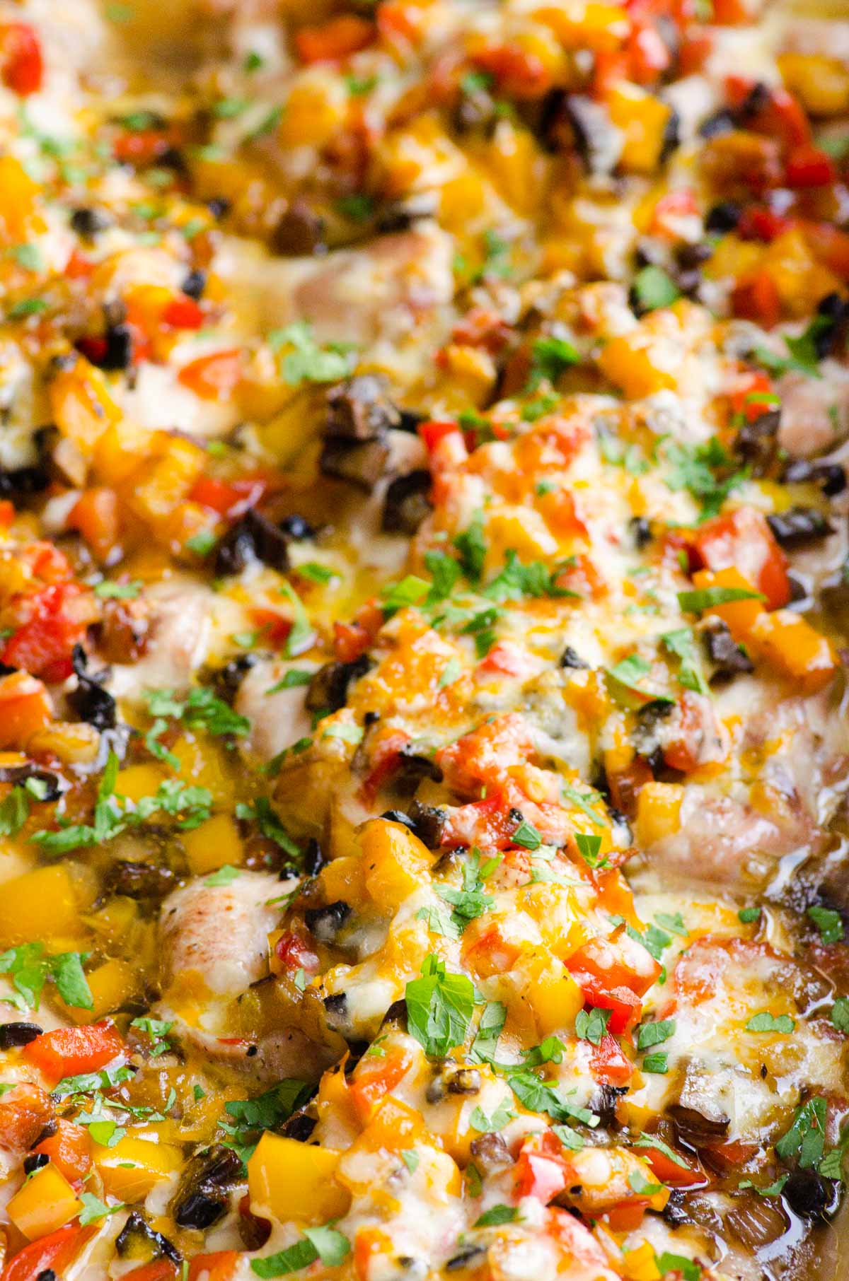 Close up of baked chicken and peppers garnished with parsley.