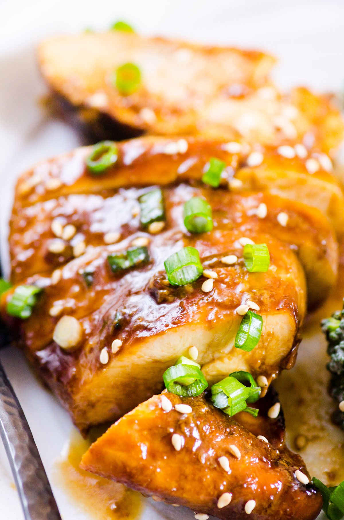 Baked honey garlic chicken breast sliced with green onion and sesame seeds.