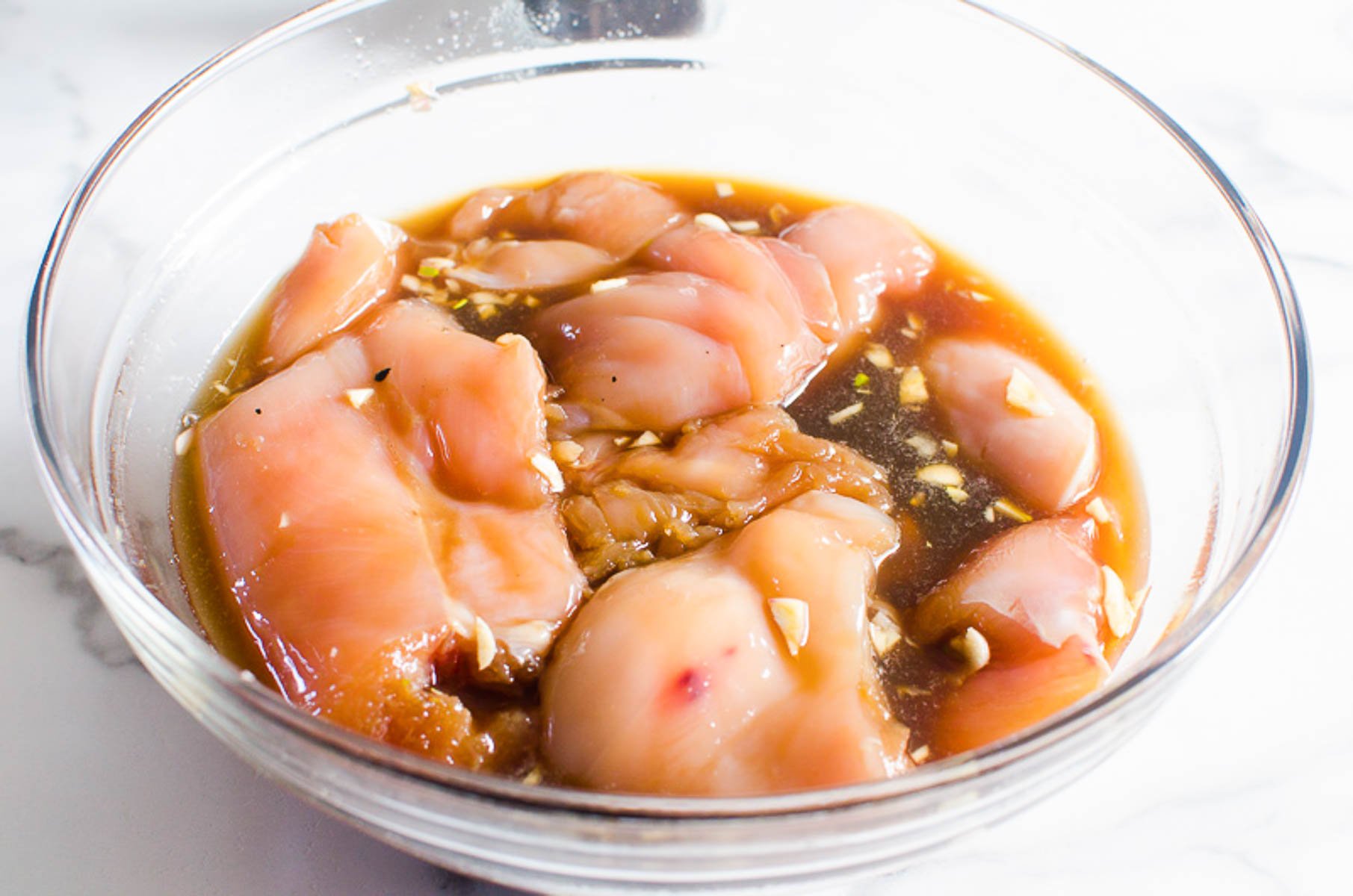 Chicken pieces marinating in a bowl.