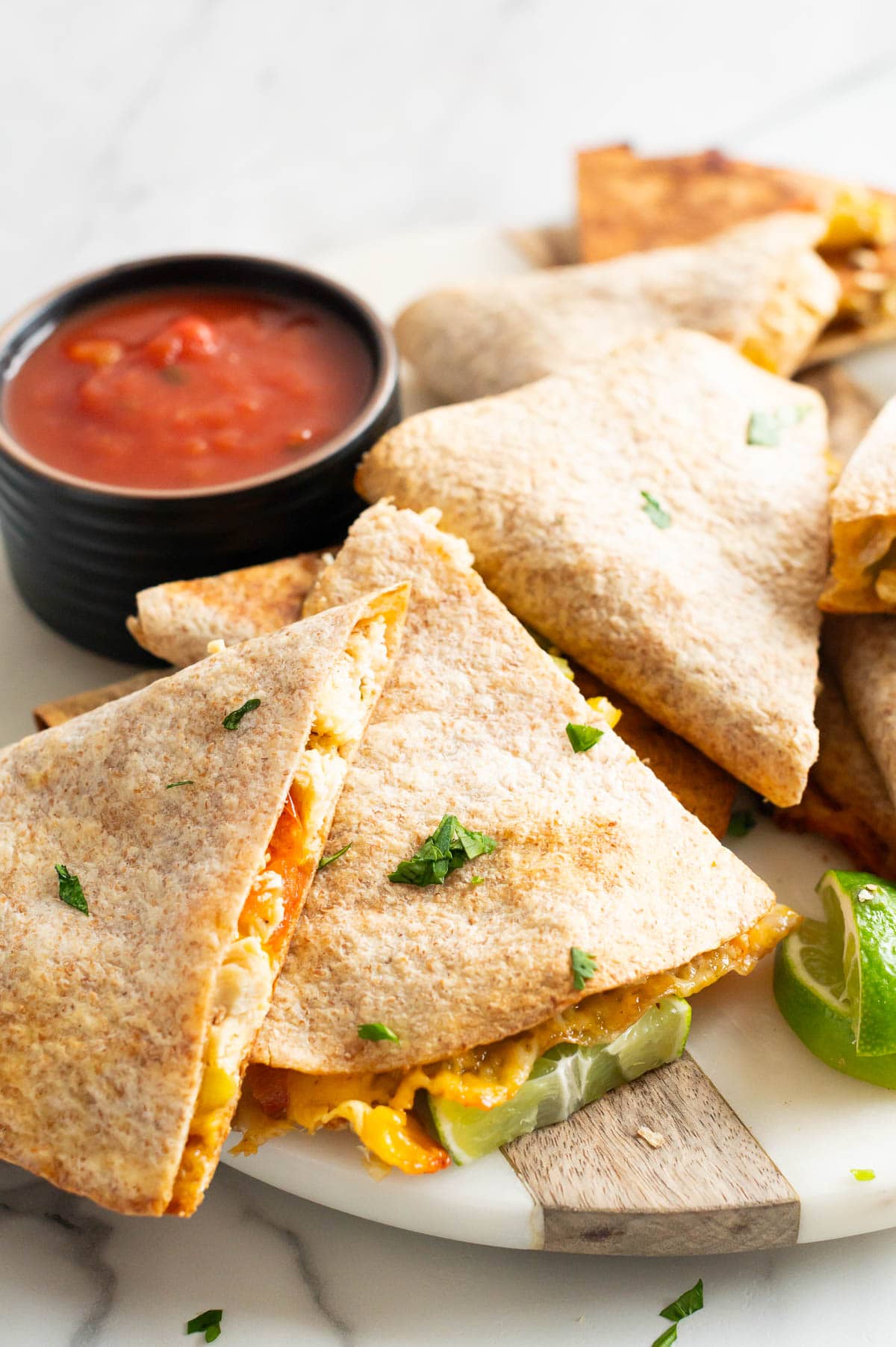 Chicken quesadillas garnished with cilantro and lime.