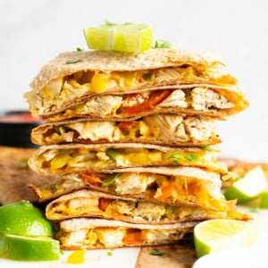 A stack of chicken quesadillas garnished with lime.