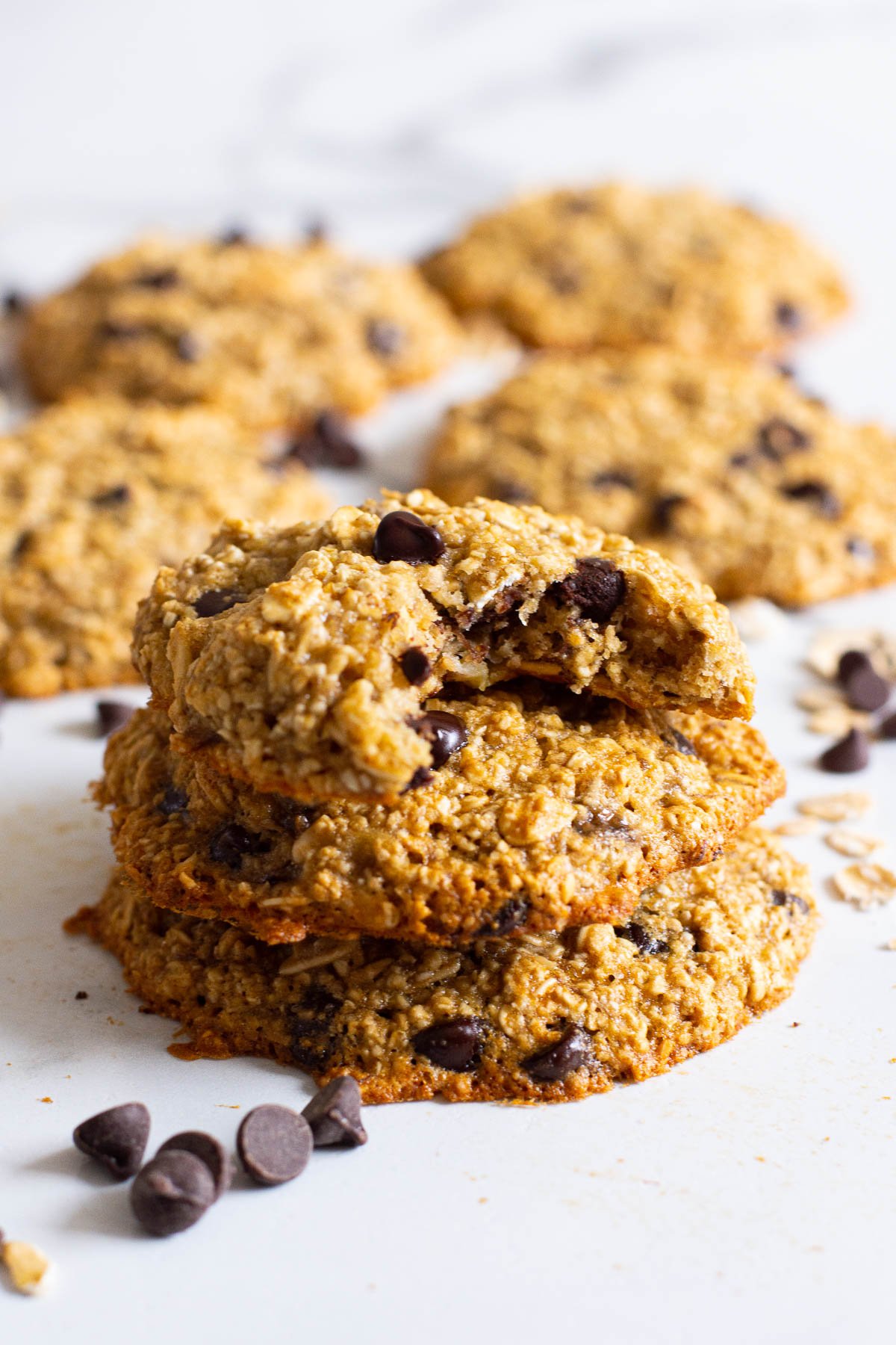 Three banana oat cookies stacked and the top one missing a bite.