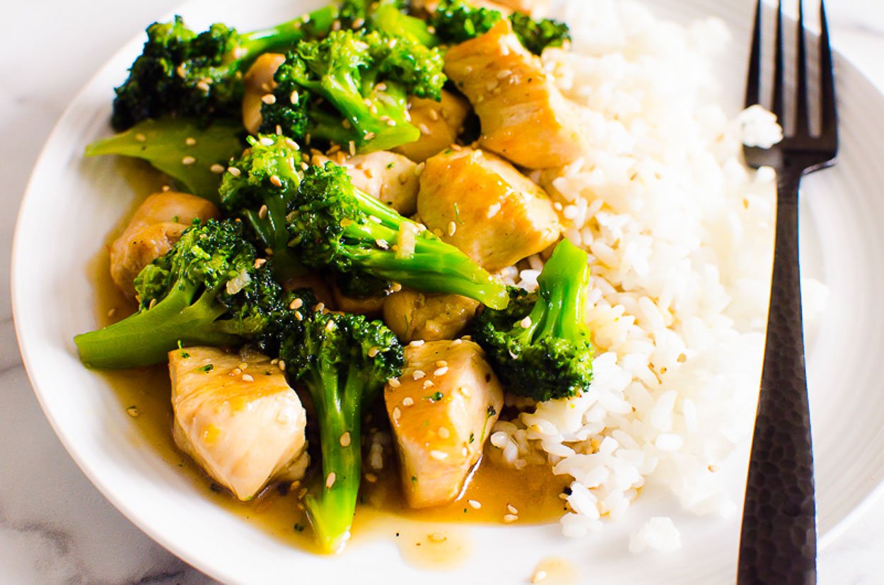 Chicken stir fry and broccoli served with rice on a plate.