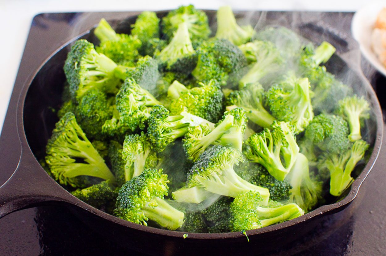 adding broccoli to skillet for broccoli stir fry with chicken