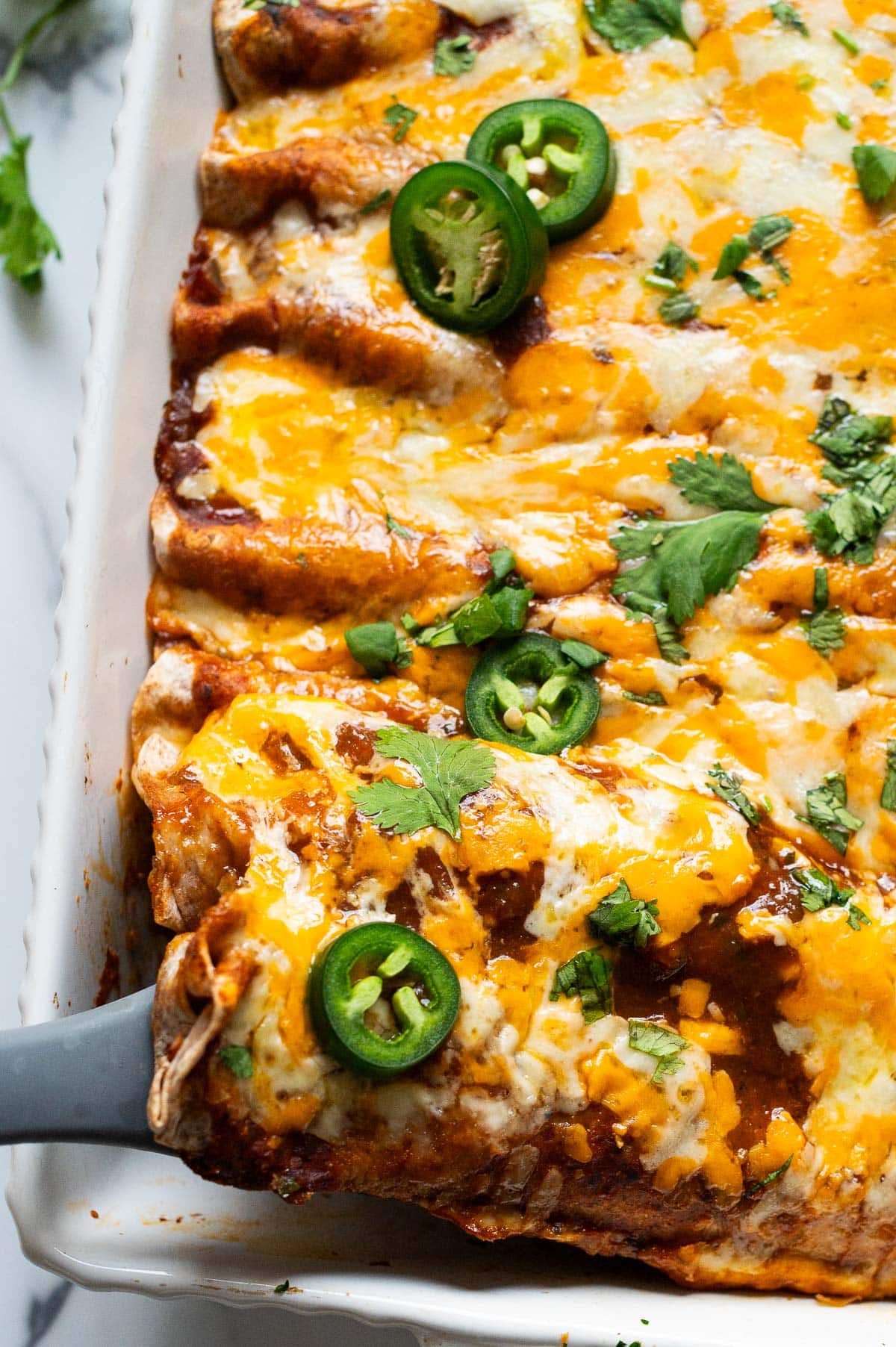 Closeup of chicken enchiladas in a baking dish.