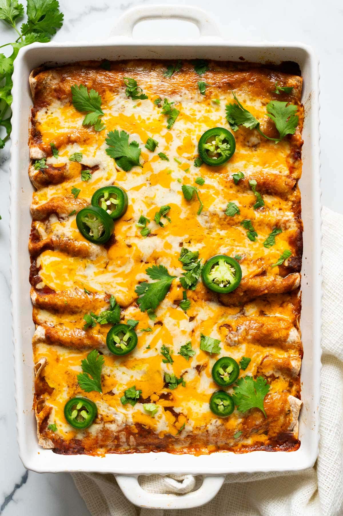 Healthy chicken enchiladas with melted cheese, cilantro and jalapeno on top.