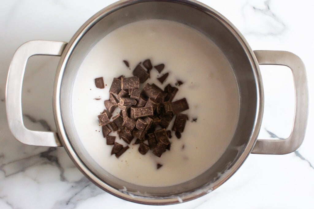 Adding chocolate to coconut milk in saucepan. 