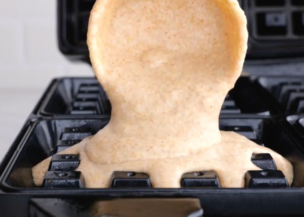 Pouring waffle batter into waffle maker.