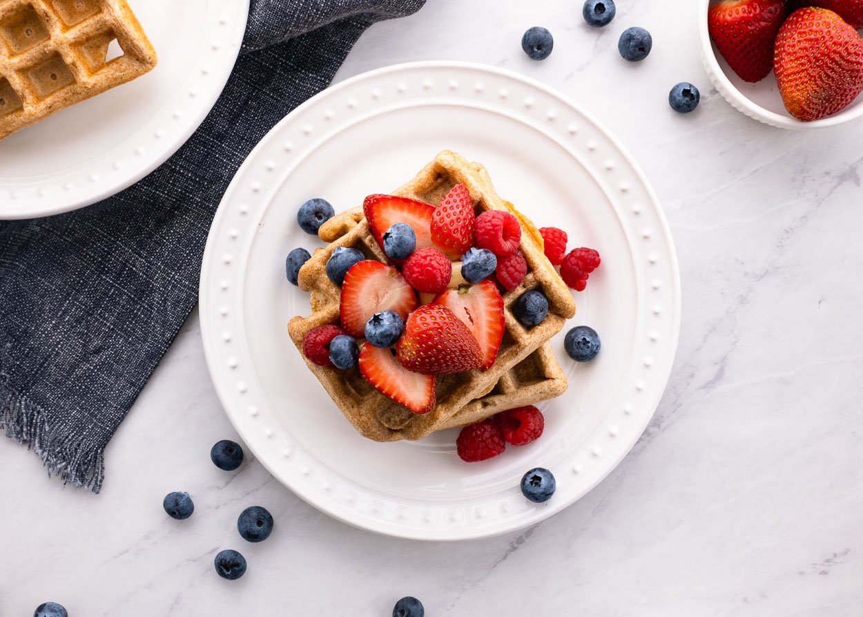 Healthy waffles on a plate with fresh berries for serving.