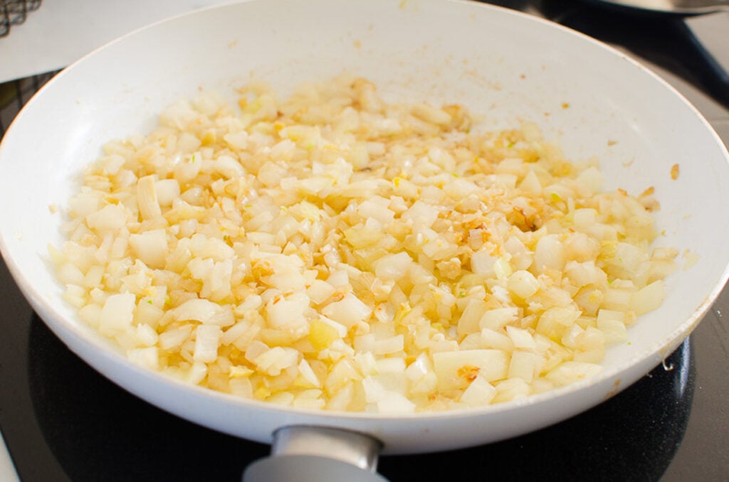 Sauteing onion in pan on stove.