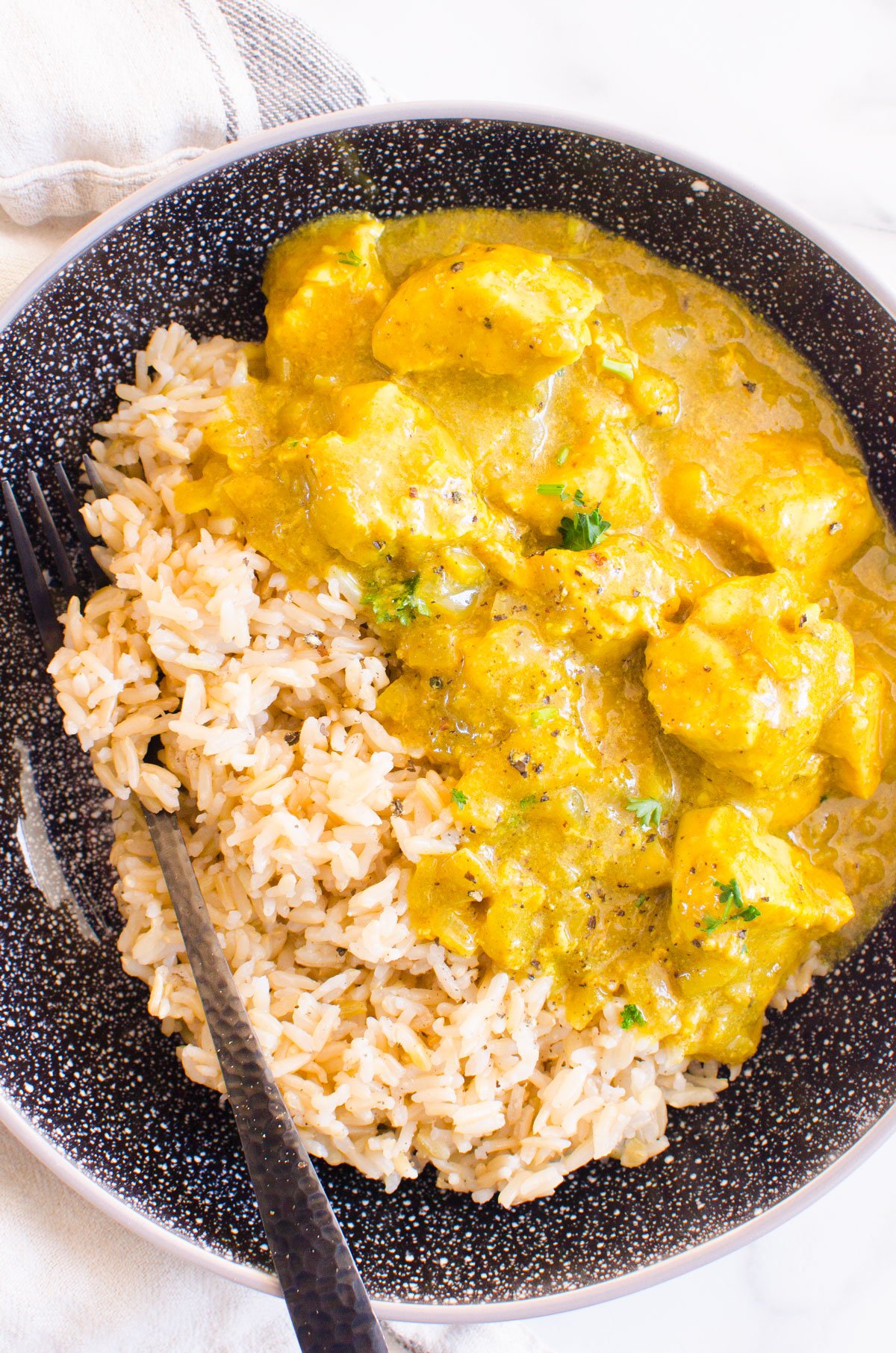 Yellow curry chicken recipe served with rice in a bowl with fork.