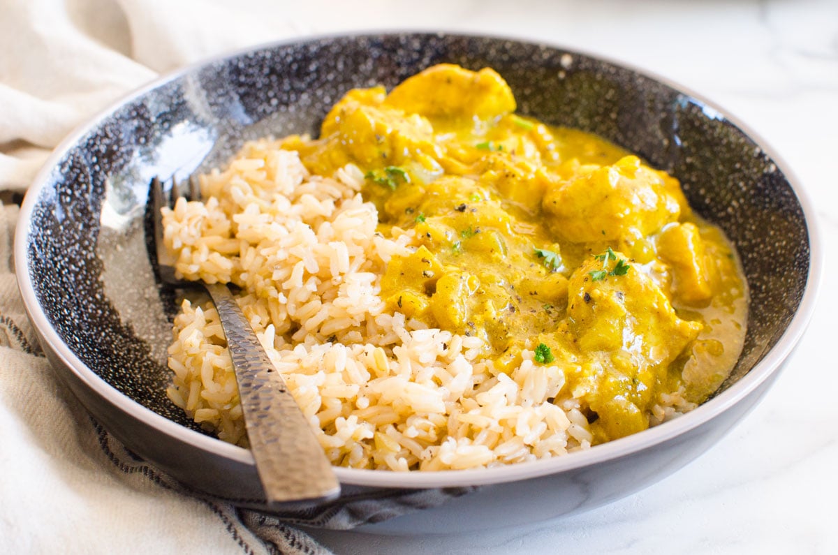 Yellow chicken curry with rice in a bowl with fork.