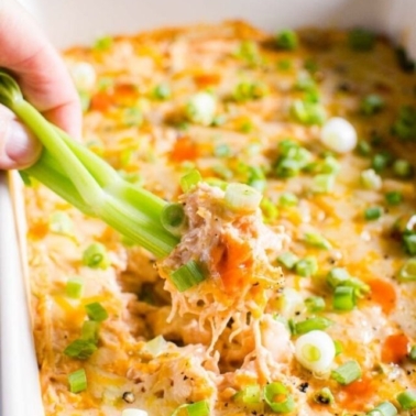 healthy buffalo chicken dip being dipped into with a celery stick