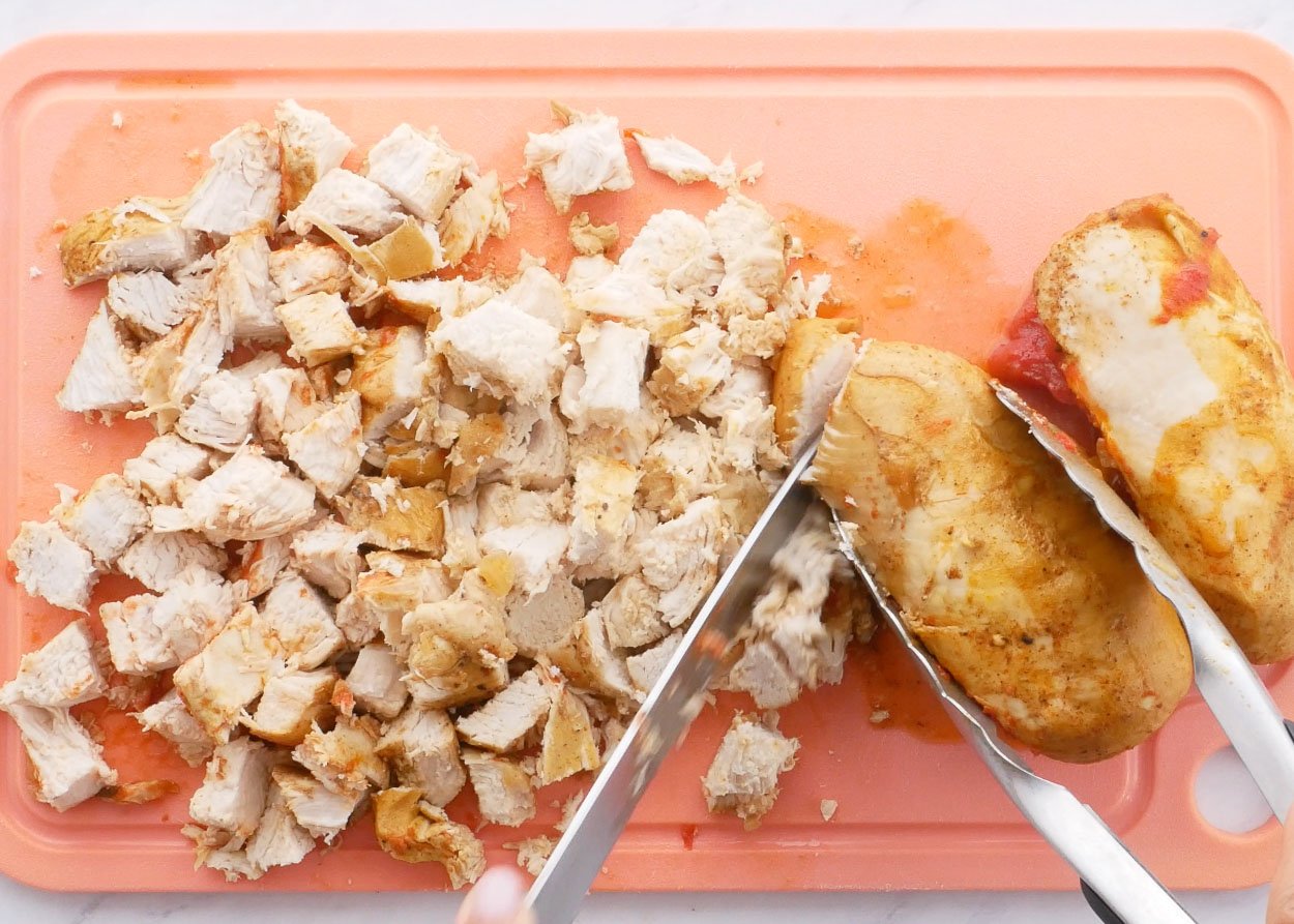 Cutting chicken on cutting board.