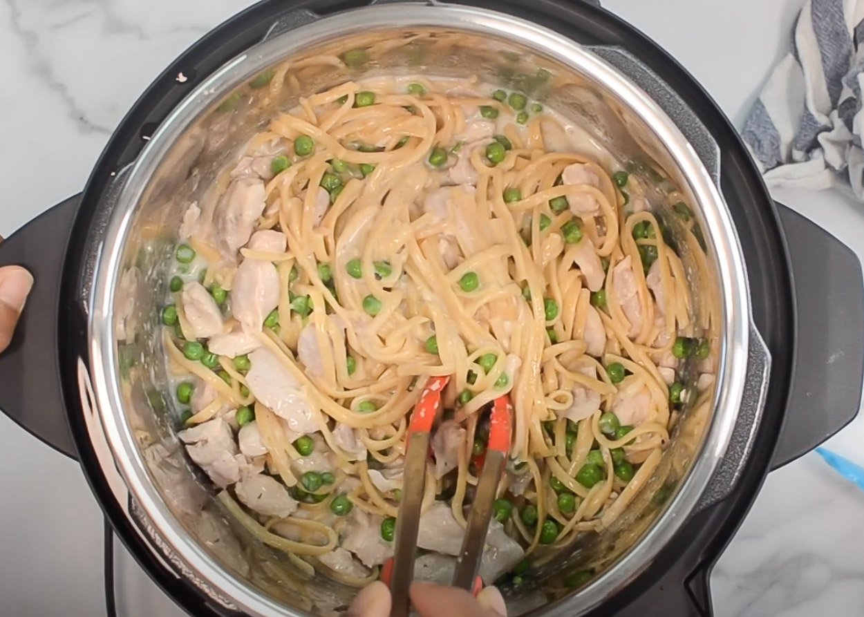 Stirring pasta, chicken and peas in Instant Pot. 