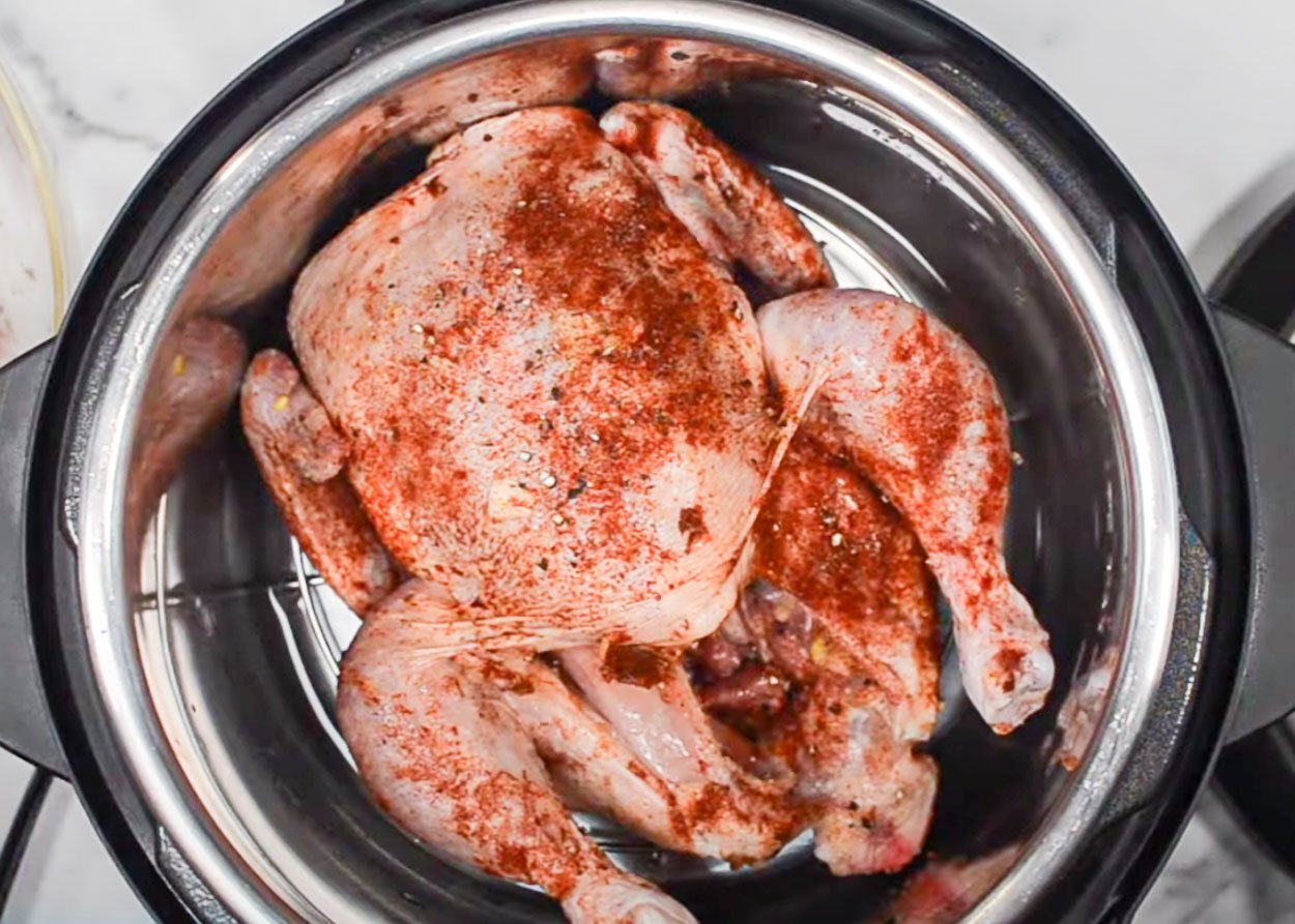 Seasoned whole chicken inside Instant Pot on a trivet.