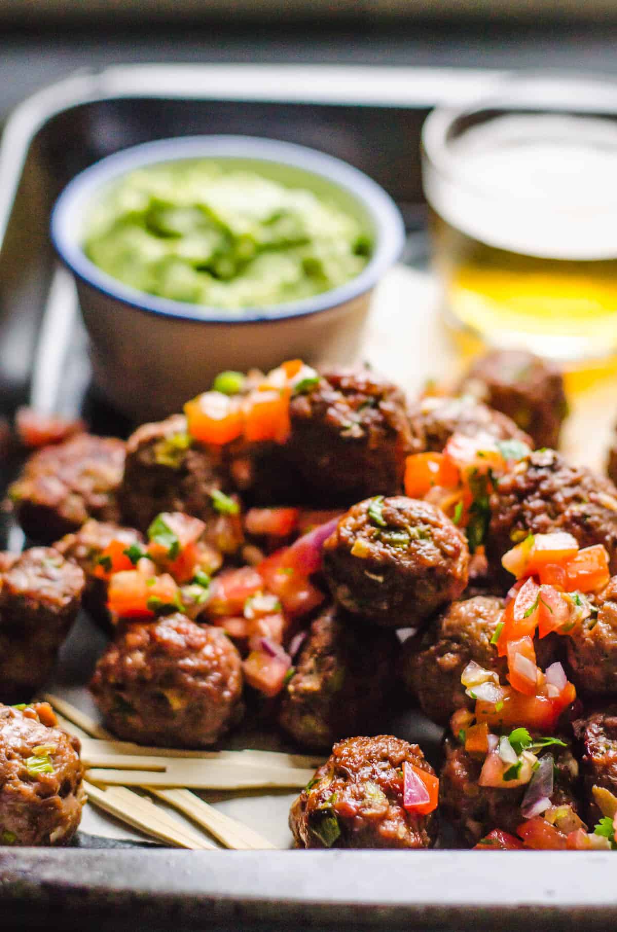 Mexican meatballs on a serving tray garnished with pico.