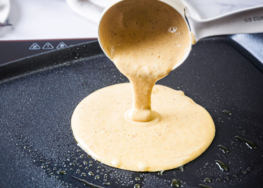 Batter being poured on griddle for healthy pancakes.
