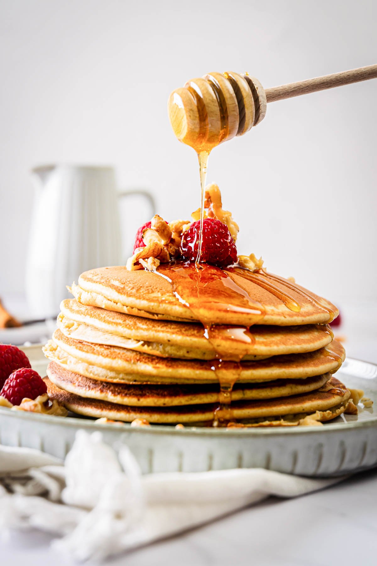 A stack of protein pancakes topped with berries and drizzled with honey.