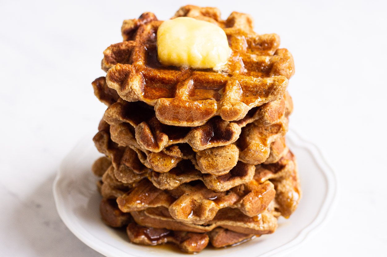 Almond flour waffles stacked high on a plate ready to eat.