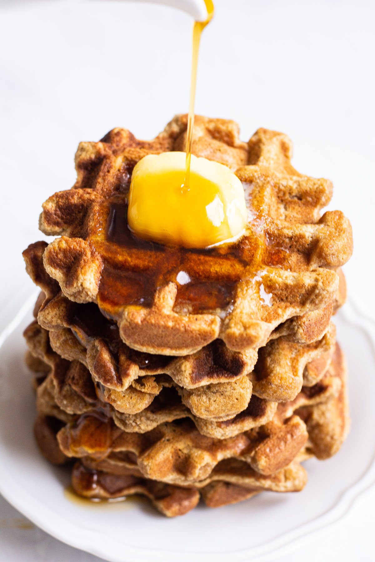 Almond flour waffles with syrup being drizzled on from above.