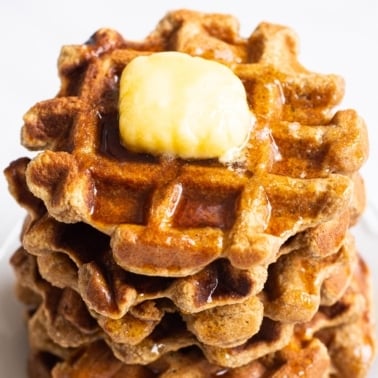 almond flour waffles stacked with pat of butter on top and syrup
