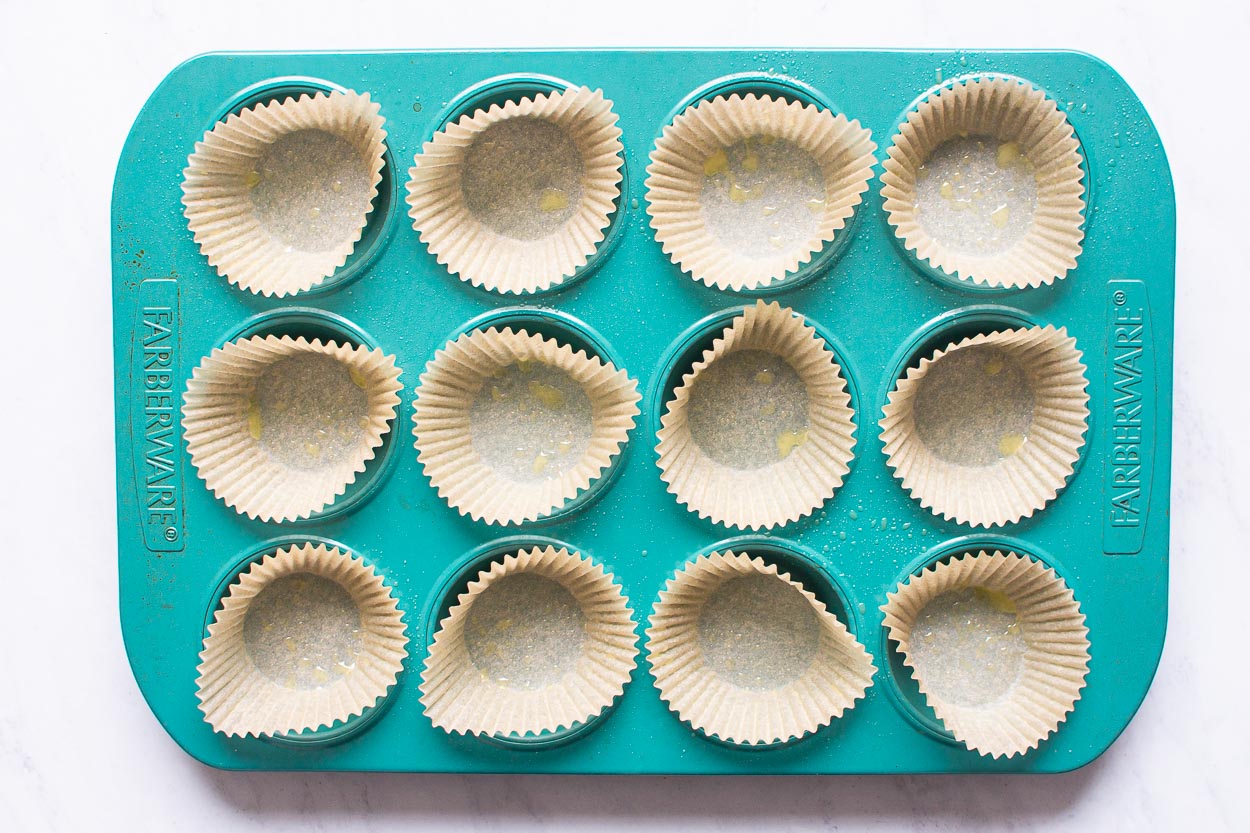 Blue muffin tin lined with parchment paper liners and sprayed with cooking spray.