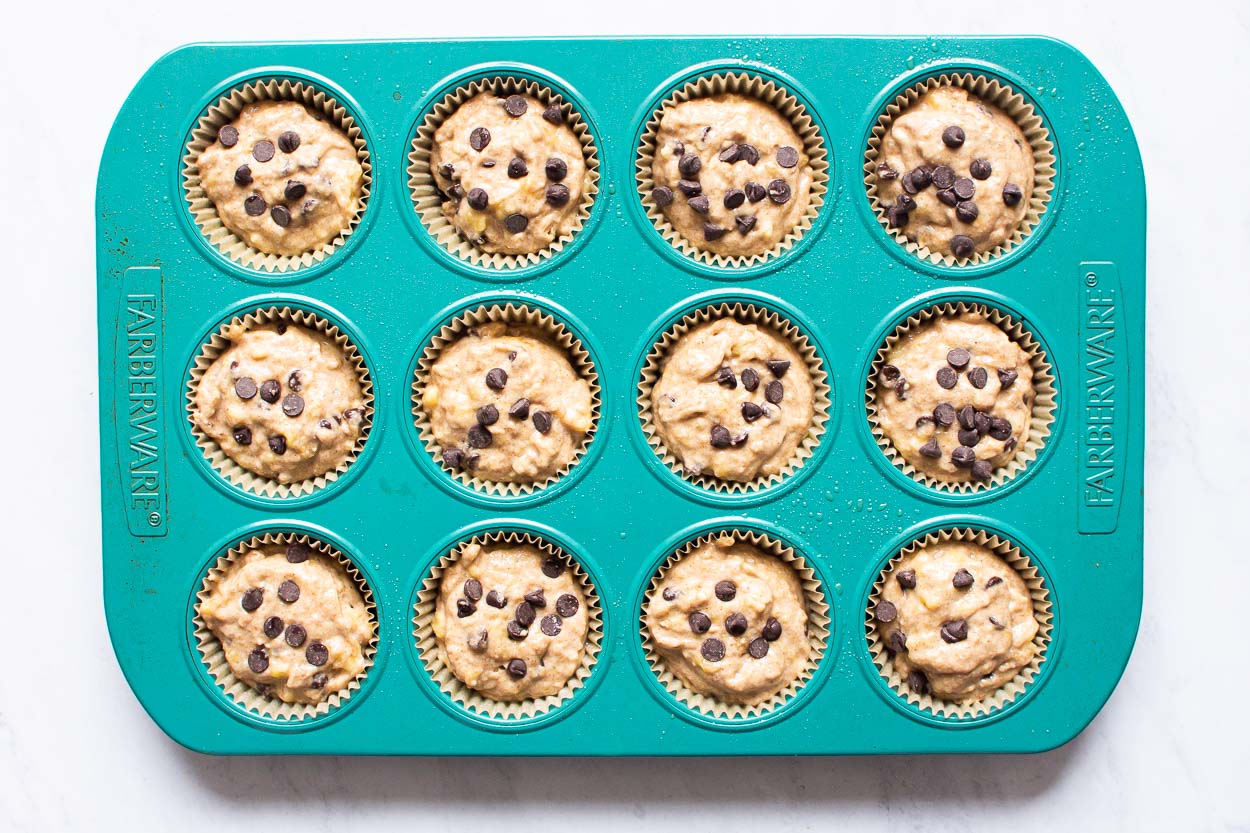 Muffins batter divided between openings of blue muffin tin.