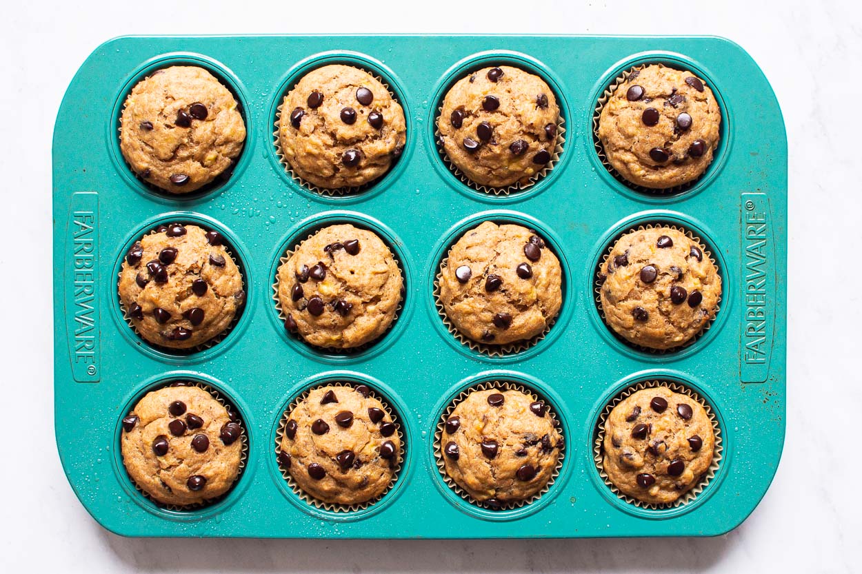 Blue muffin tin with baked healthy banana chocolate chip muffins.