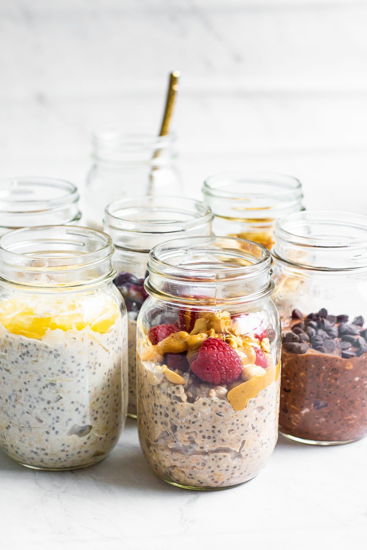 Healthy overnight oats with yogurt, chia seeds and toppings in glass jars.
