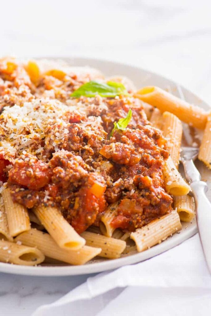 A plate of pasta with meat sauce and fresh basil. 