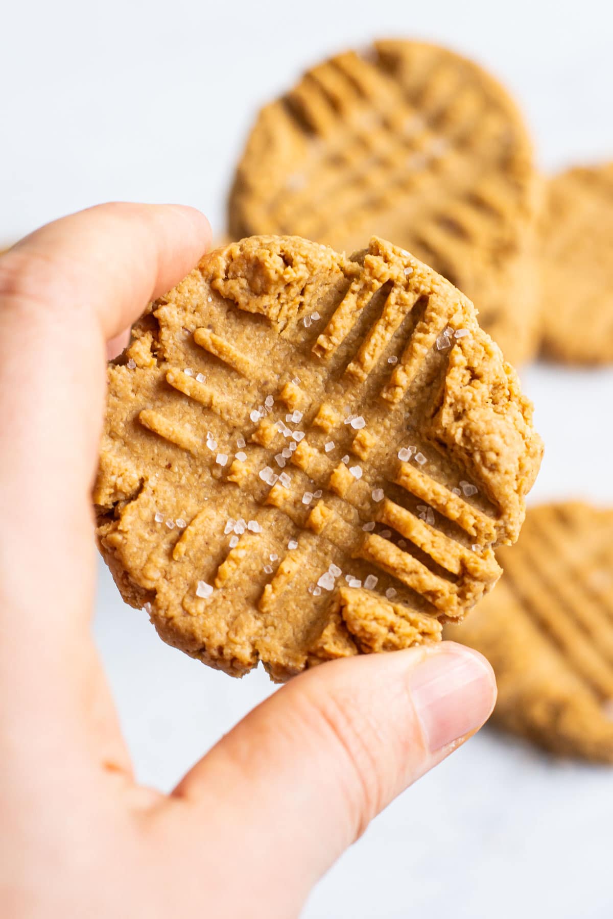 Holding healthy peanut butter cookie sprinkled with sea salt in hand.