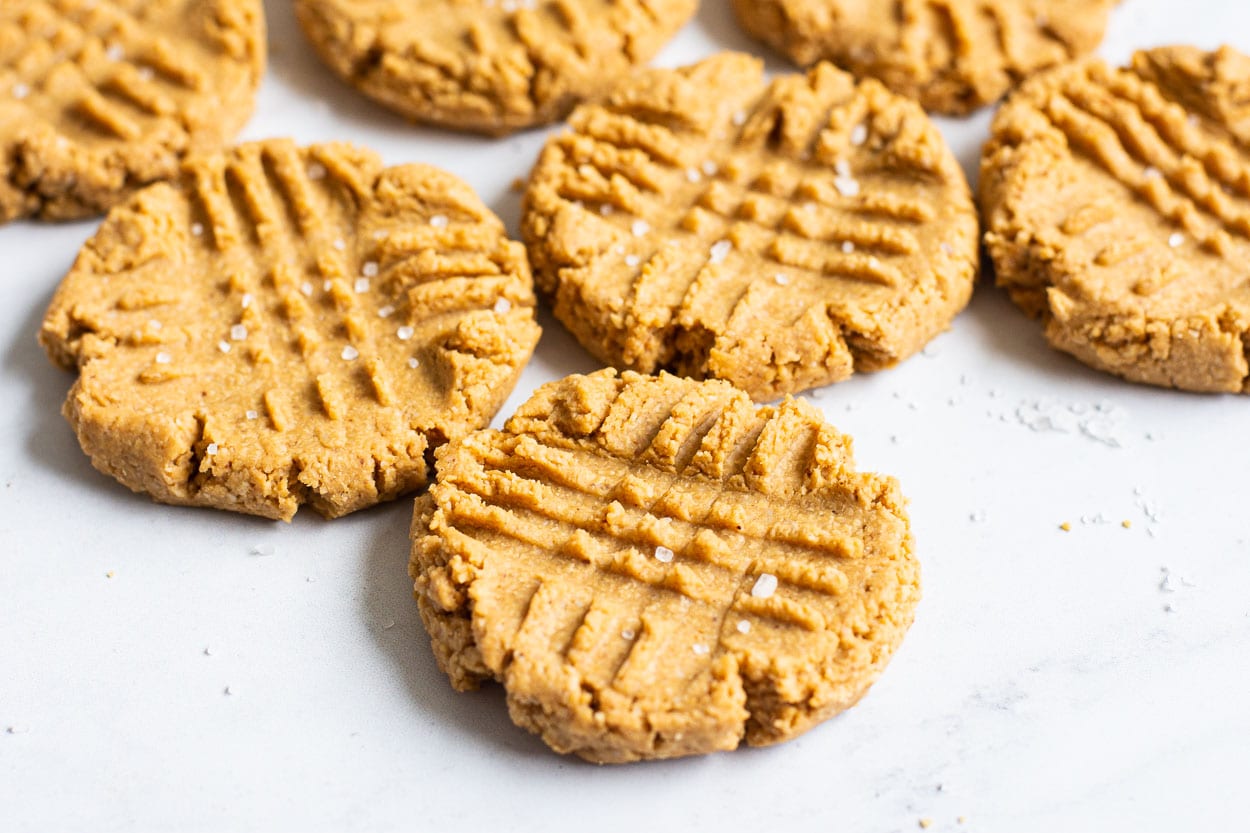 Peanut butter cookies with sprinkles of salt on a countertop.