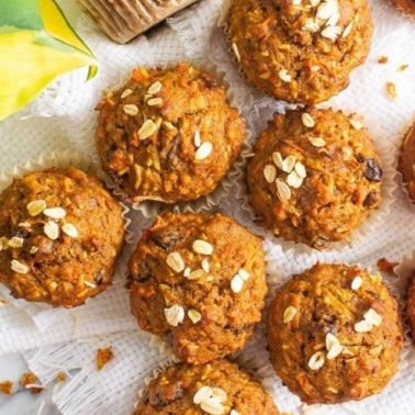 looking down at seven morning glory muffins with crumbs around muffins on a white linen.